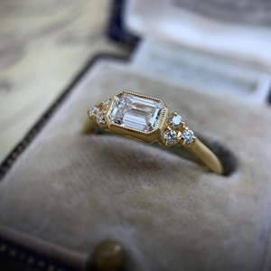 Macro shot of gold vintage ring with emerald-cut zirconia and milgrain texture