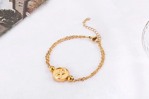 Close-up of a gold infinity symbol pendant on a double-layer stainless steel bracelet