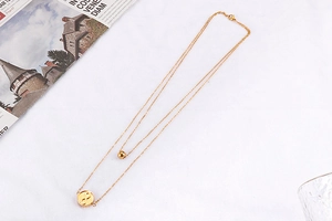 Flat lay of a gold double-layer necklace with infinity pendant on white textured fabric