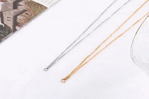 Detail of silver and gold double-layer number 8 chains on soft white fabric background
