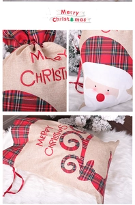 Detail of Christmas burlap gift bag with Santa Claus embroidery and red plaid trim