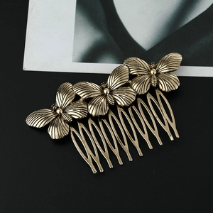 Detailed view of vintage gold alloy butterfly hair comb on a matte black surface