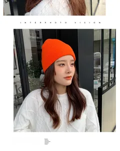 Detailed knit texture of a vibrant orange ribbed daisy beanie on a female model