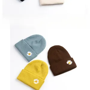 Detailed knit texture and daisy embroidery on blue, yellow, and brown beanies