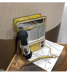Macro detail of retro phone shaped bag in metallic gold and silver with chain strap