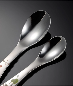 Close-up of polished stainless steel kids spoons with floral cartoon handle engraving