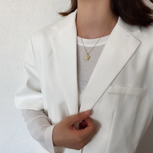 Close-up of a 925 sterling silver irregular coin necklace on a model wearing a white suit