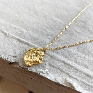 Close-up of golden irregular textured pendant with artistic hammered metal finish