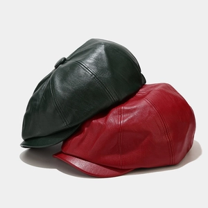 Detailed view of dark green and red leather newsboy caps with lychee grain texture