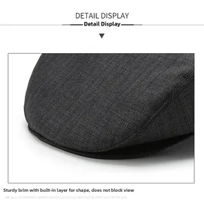 Détail de la visière robuste d'une casquette plate gris foncé montrant le tissu tissé