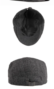 Détail de la casquette plate en laine gris foncé avec sangle réglable en cuir et boucle