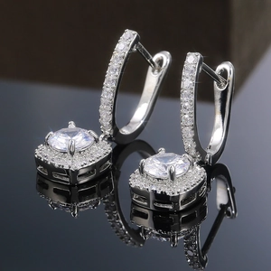 Gros plan de boucles d'oreilles carrées halo argentées avec zircons sur miroir noir brillant