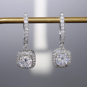 Détails rapprochés de boucles d'oreilles géométriques avec pierres rondes et halo