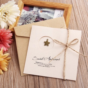 Artistic handmade greeting card with craft envelope and a metal star pendant detail
