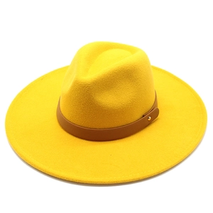 Detailed macro shot of yellow wool fedora hat with brown leather band and gold rivets