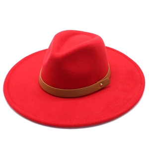 Detail view of red wool fedora hat with wide brim, brown leather band and gold rivet