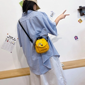 Yellow canvas crossbody bag with rainbow detail and adjustable strap shown on model