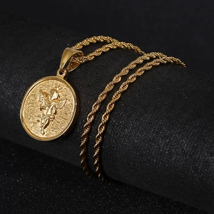 Détail du pendentif ange doré en acier inoxydable et chaîne torsadée sur fond texturé