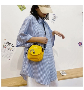 Detail of yellow canvas crossbody bag with rainbow patch and black shoulder strap