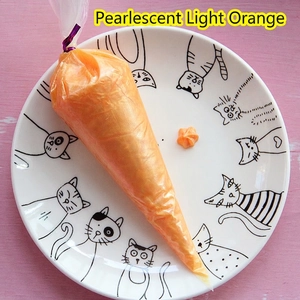 Detail of pearlescent light orange cream glue in a piping bag with star pattern on plate