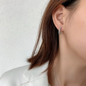 Macro detail of 925 sterling silver C-shaped earrings with full pavé diamond setting