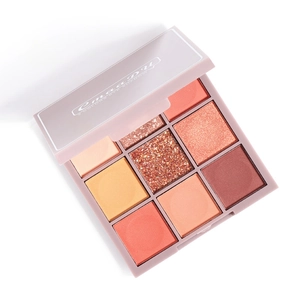 Macro detail of a 9-color eyeshadow palette featuring peach and orange matte and shimmer tones