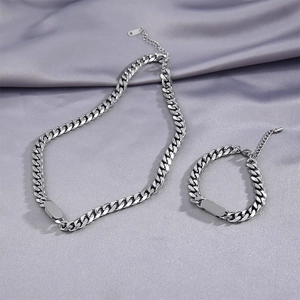 Detailed view of silver Cuban chain set with rectangle tags on grey silk background