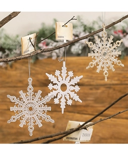 Detailed view of white, gold, and clear snowflake ornaments hanging on rustic branches