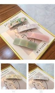 Close-up of 8.5cm acetate hair clips in cream white and gemstone white marble patterns