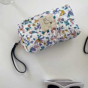 Borsa da trucco trapuntata a fiori con manico nero su scrivania con accessori