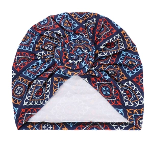 Detail of blue turban hat with orange geometric print and 3D spiral flower design