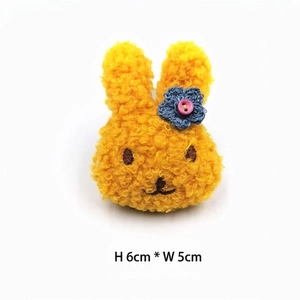 Gelbes Plüsch-Hasen-Accessoire mit blauer Häkelblume, Höhe 6 cm und Breite 5 cm, Detail