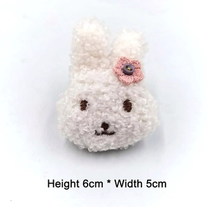 Detail eines weißen Plüschhasen mit rosa Häkelblume, Größe 6 cm hoch und 5 cm breit
