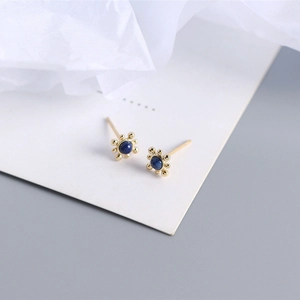 Macro shot of gold S925 silver stud earrings with natural round blue lapis lazuli