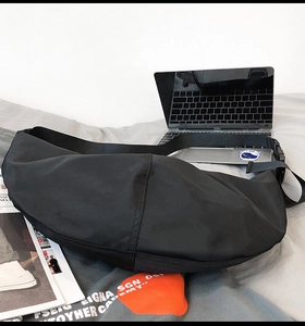 Detail of black nylon crossbody bag with adjustable strap on a lifestyle background