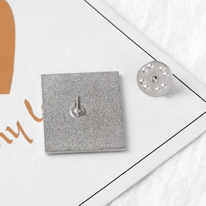Metallic letter brooch back showing silver pin base and butterfly clutch fastener
