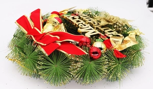 Détail d'une couronne de Noël avec inscription dorée, nœuds rouges et boules brillantes