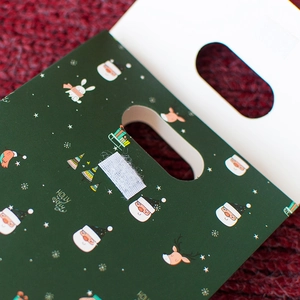Green Christmas paper gift bag with cute Santa and reindeer patterns and Holly Jolly text