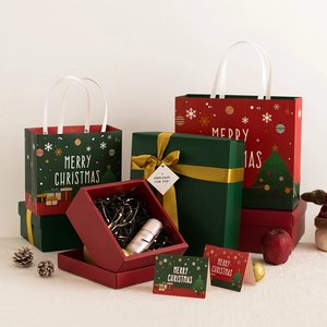 Set de regalo navideño con bolsas de papel rojas y verdes, tarjetas de felicitación y caja.