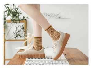 Detail of yellow plaid crew socks paired with platform gum sole sneakers in warm setting