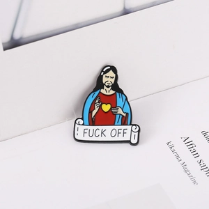 Détail macro d'un pin's en émail avec personnage religieux cartoon et parchemin amusant