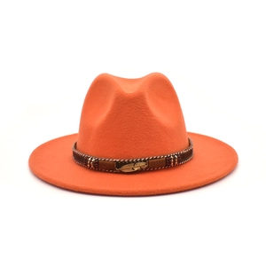 Close-up of orange wool fedora featuring brown braided band and gold feather charm