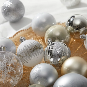 Silver and white Christmas ball ornaments with snowflake patterns on a golden tray