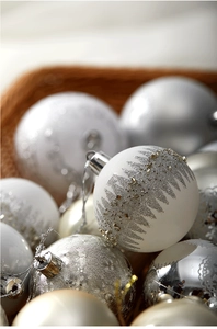 Detail of silver and white Christmas baubles with snowflake patterns in a woven basket