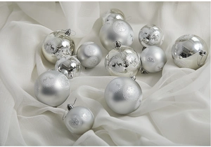 Silver Christmas ornaments with deer and snowflake patterns on elegant white silk fabric