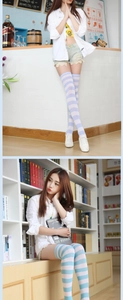 Detailed lifestyle shot of colorful striped over-the-knee socks worn by a model in a casual setting.