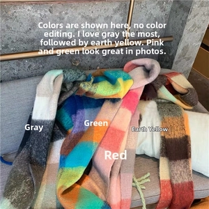 Detailed close-up of rainbow plaid scarves in grey, green, red and tan with fringe edges