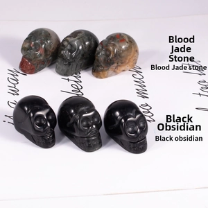 Close-up of hand-carved skulls in blood jade and black obsidian on display card