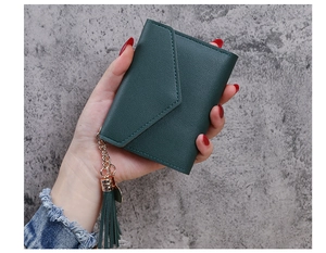 Detail of dark green pebbled leather wallet featuring tassel pendant and gold chain strap