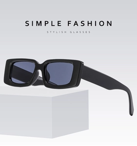 Close-up of retro square sunglasses with thick black frames and dark blue lenses on stone